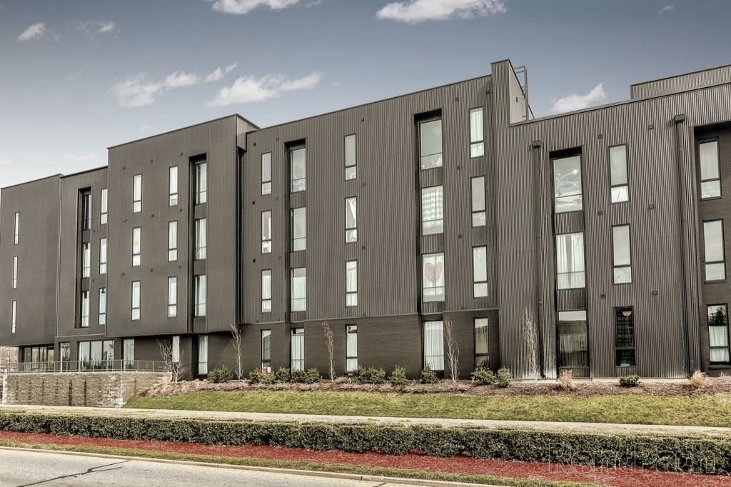 A large apartment building with a lot of windows is sitting next to a road.