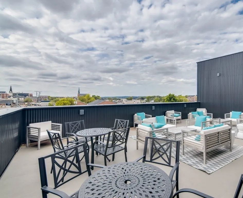 There are tables and chairs on the roof of a building.