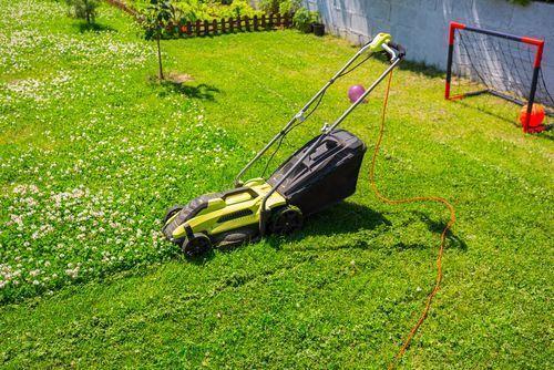 A lawn mower is sitting on top of a lush green lawn.