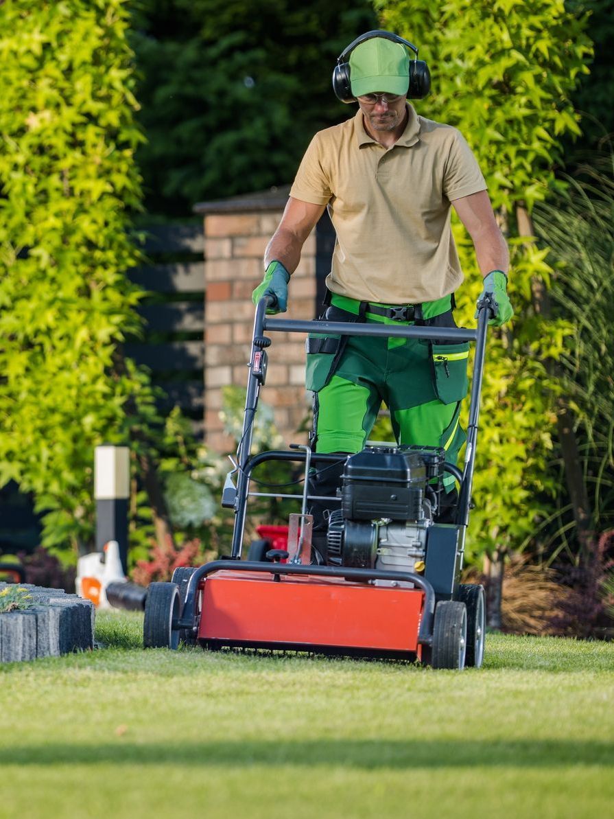 A man is cutting a lush green lawn with a lawn mower.