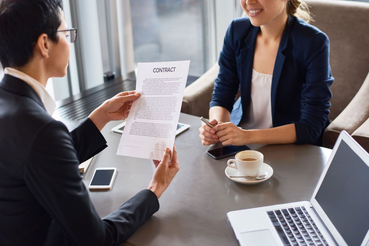A man and a woman are sitting at a table with a laptop . the woman is holding a piece of paper.