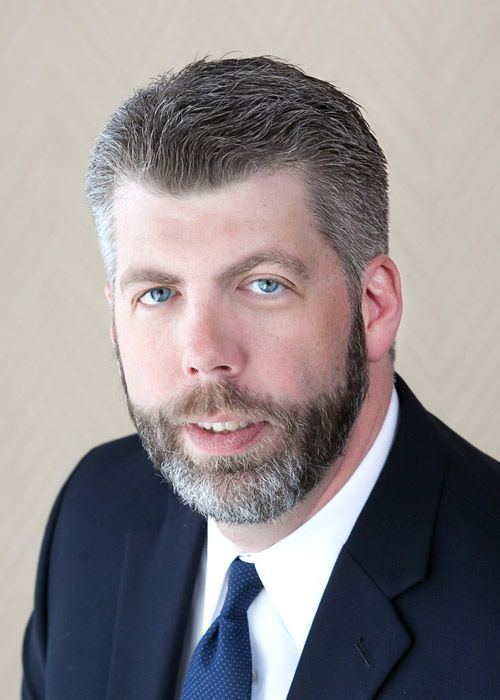 A man with a beard is wearing a suit and tie