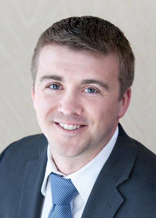 A man in a suit and tie is smiling for the camera