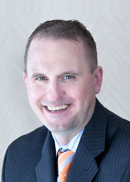 A man in a suit and tie is smiling for the camera