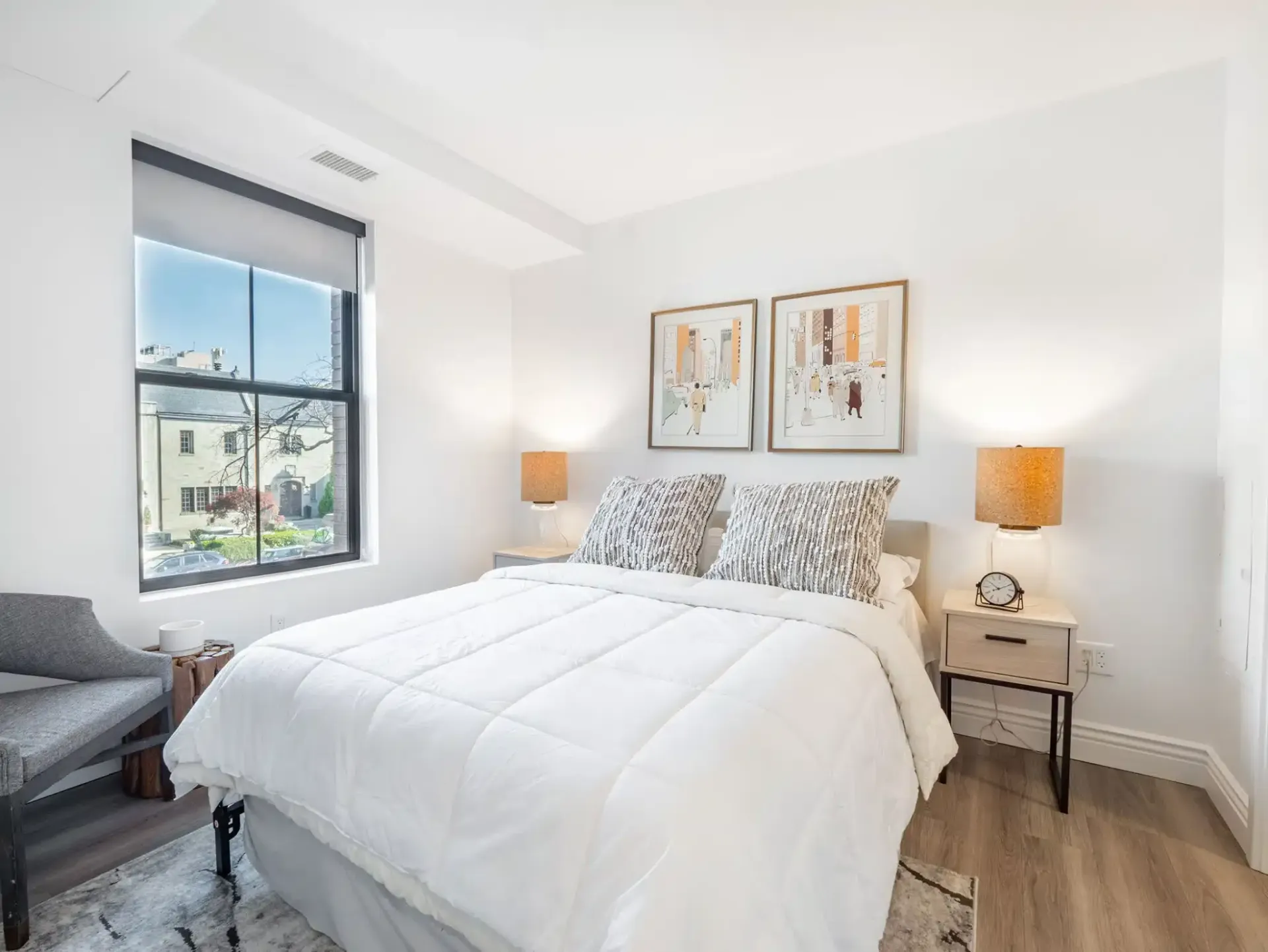 A bedroom with a bed , nightstand , chair and window.