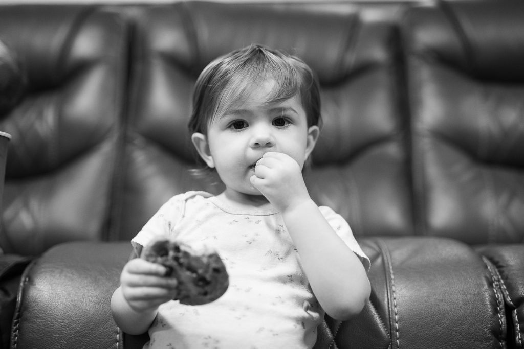 A baby is sitting on a couch eating a cookie. | Redline Automotive