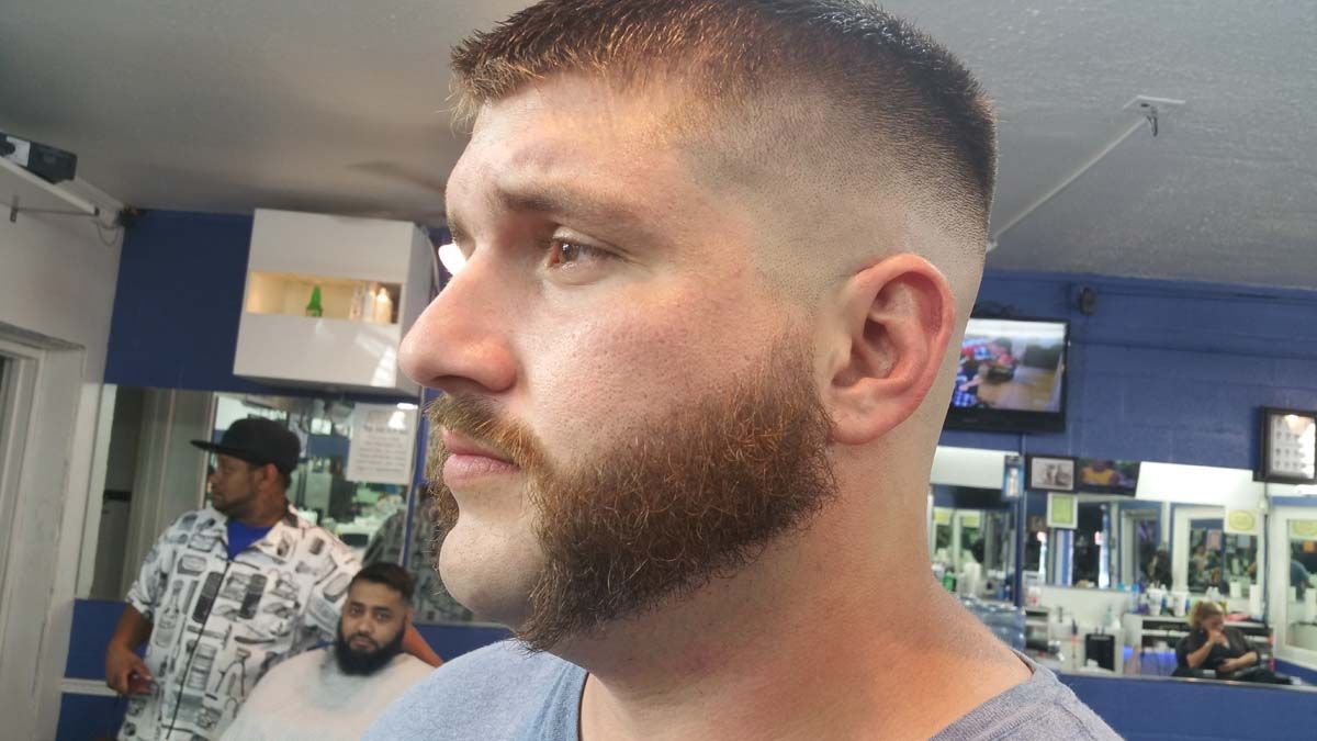 A Man With A Beard Is Getting His Hair Cut At A Barber Shop