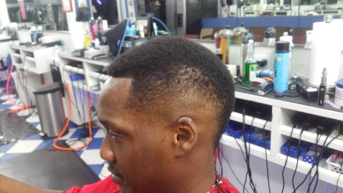 A Man Is Getting His Hair Cut In A Barber Shop