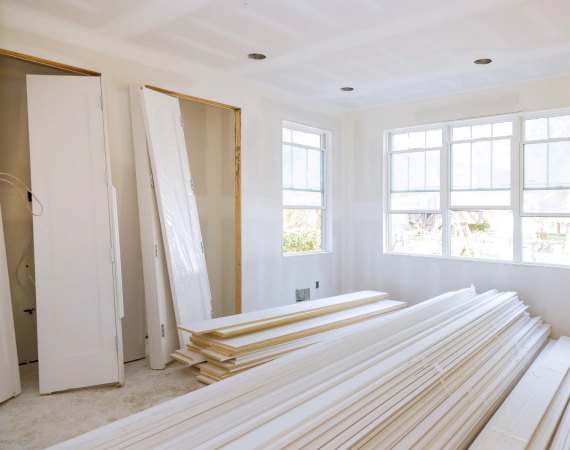 Room under construction with white trim, drywall, and windows.