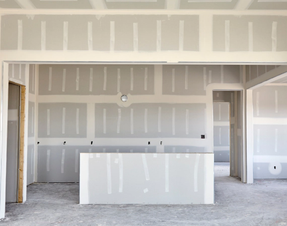 Interior construction: drywall installed on walls and ceiling, room in progress.
