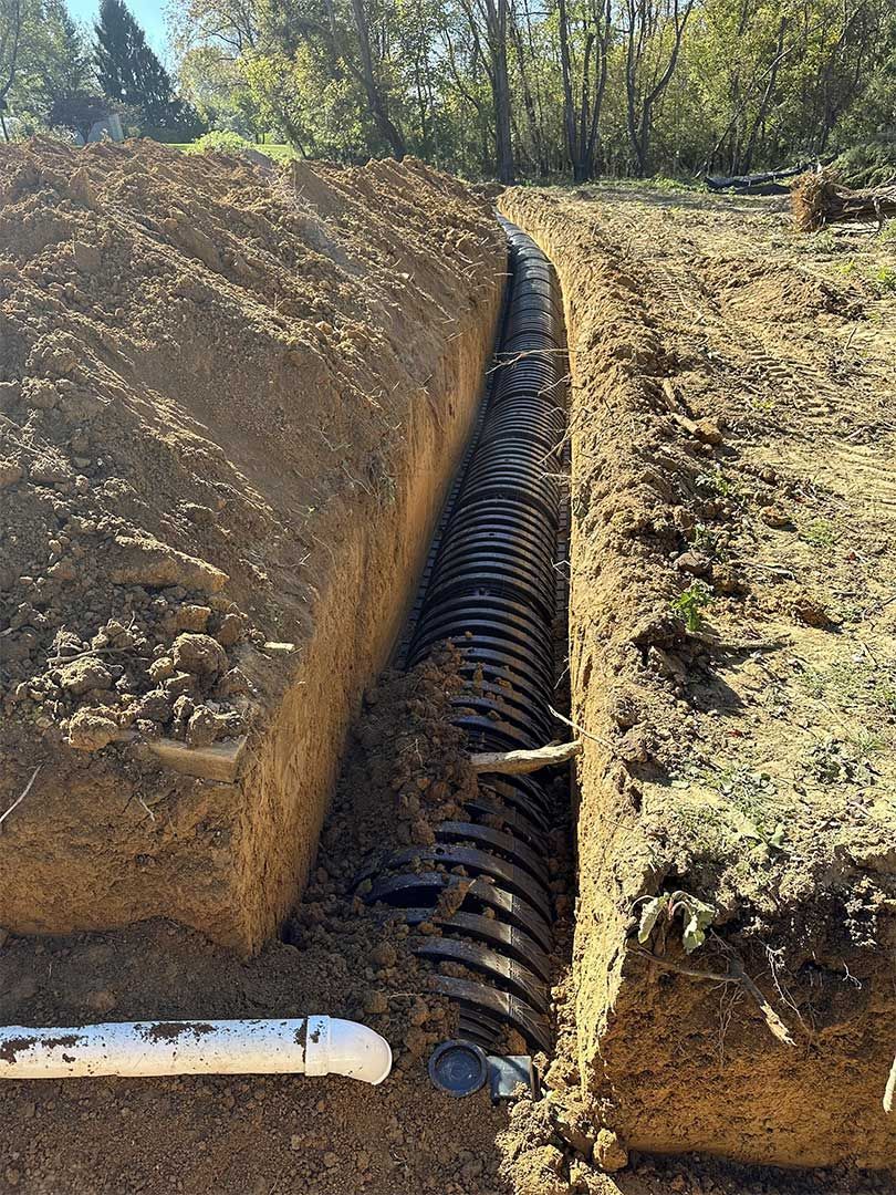 A septic system is being installed in a trench in the dirt.