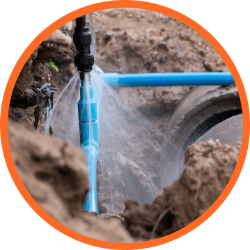 Blue water pipe leaking, spraying water. Pipe located in an excavated hole.