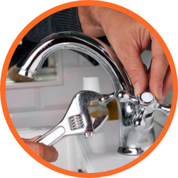 Person using a wrench to repair a shiny chrome faucet in a bathroom.