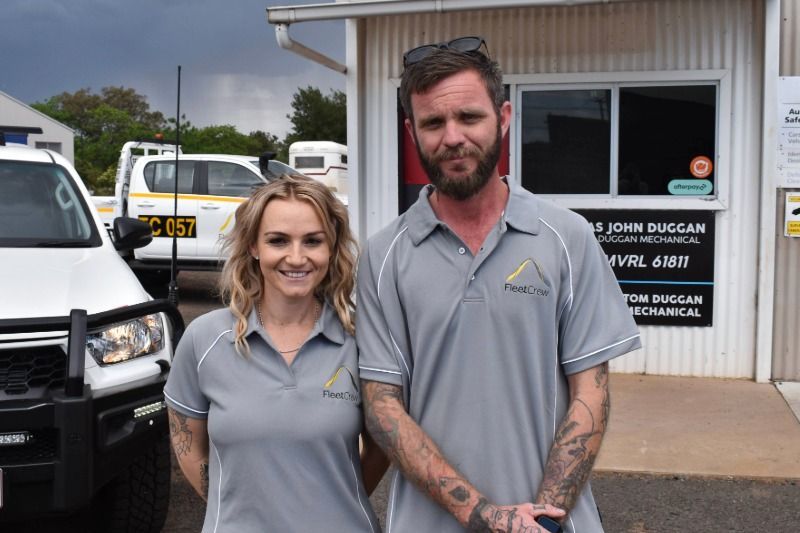 Two People in Matching Gray Work Shirts Stand Outside a Building Next to A White Truck — Tom Duggan Mechanical in Dubbo, NSW
