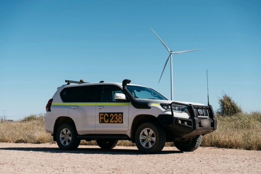 White SUV with Fc 238 on Side, Parked on Dirt Road, Wind Turbine in Background — Tom Duggan Mechanical in Dubbo, NSW