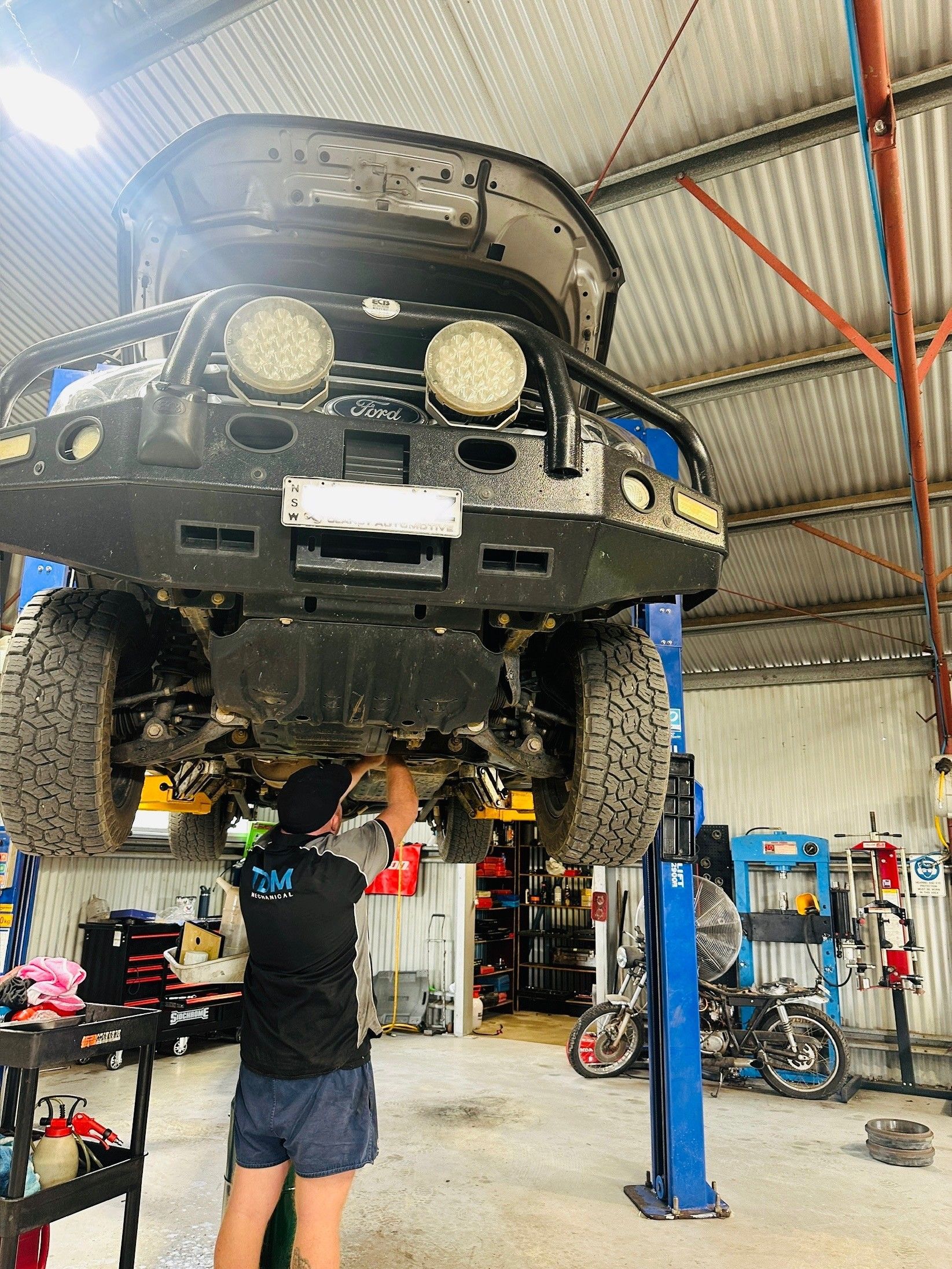 car on a lift with mechanic underneath — Tom Duggan Mechanical in Dubbo, NSW