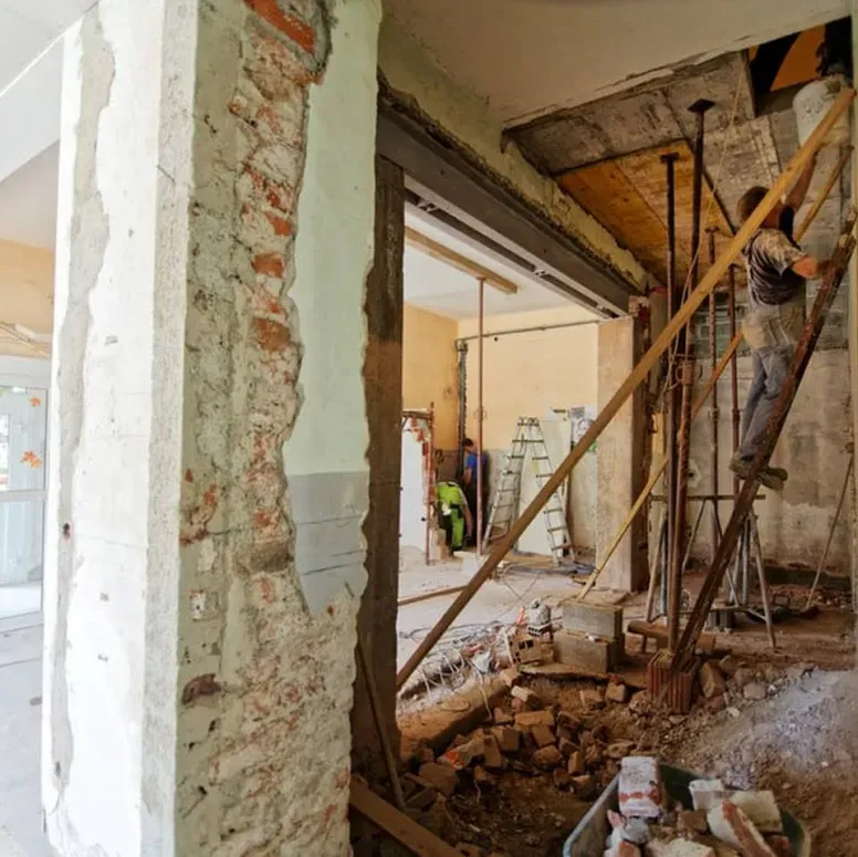 A man is standing on a ladder in a building under construction