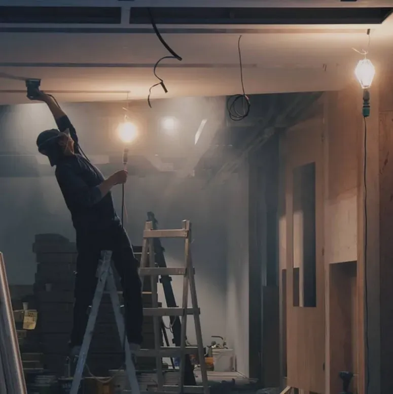 A man on a ladder working on a light bulb