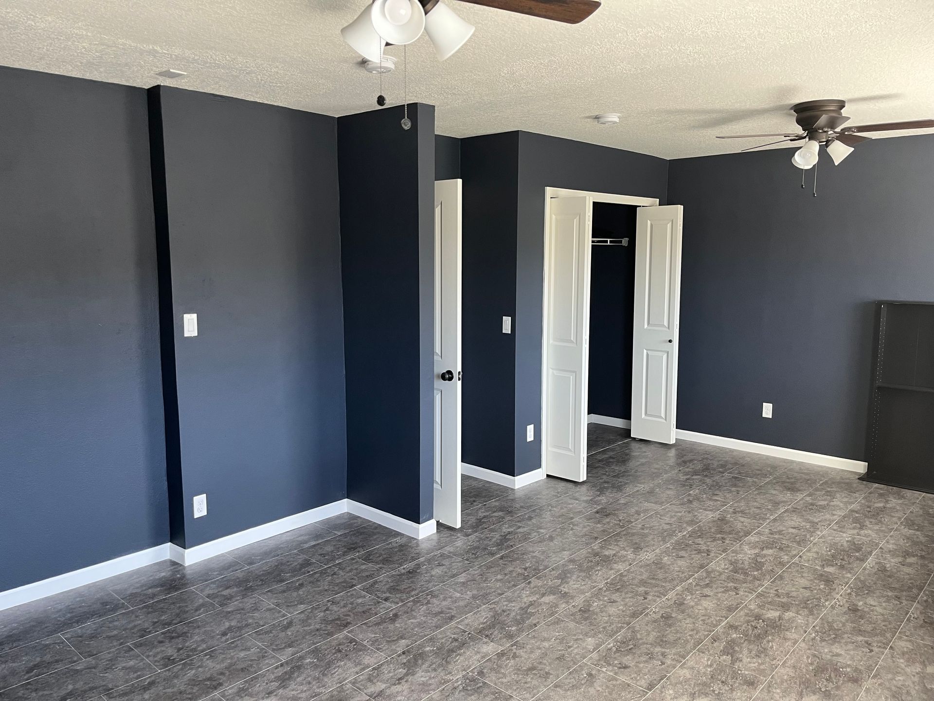 A living room with dark blue walls and a ceiling fan.