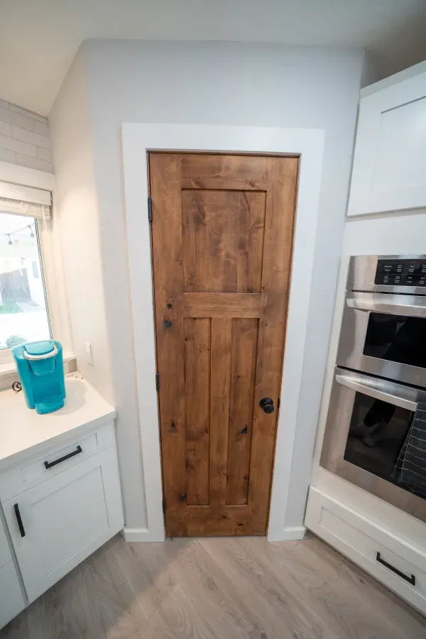 A kitchen with a wooden door and stainless steel appliances.