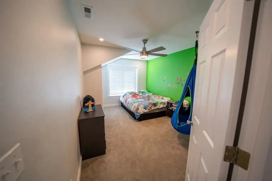 A bedroom with a bed , dresser , and ceiling fan.