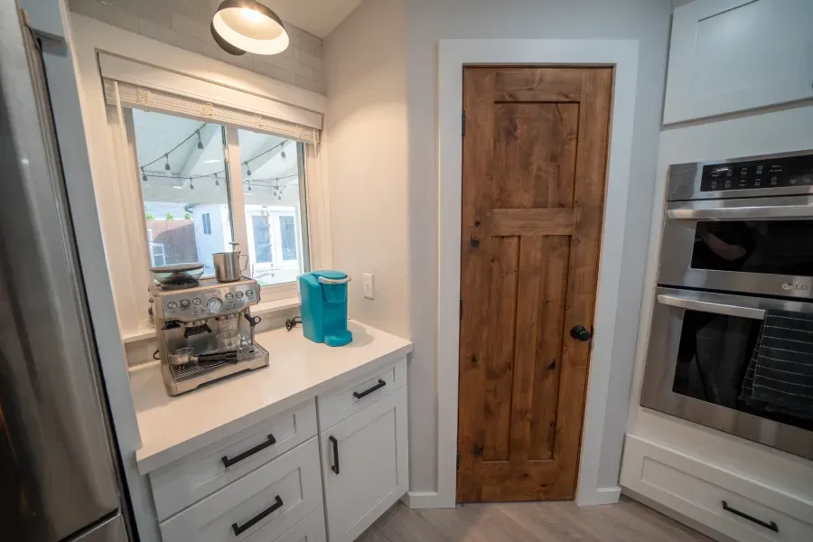 A kitchen with white cabinets , stainless steel appliances and a wooden door.