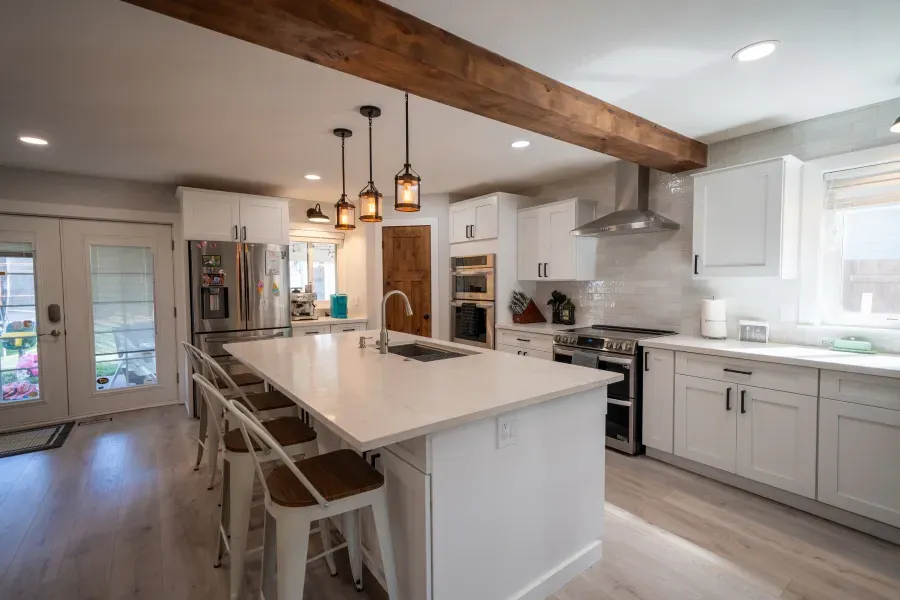 A kitchen with white cabinets , stainless steel appliances , and a large island.