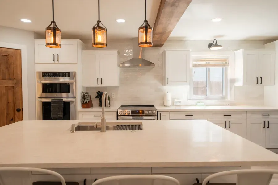A kitchen with white cabinets , stainless steel appliances , a sink , and a large island.
