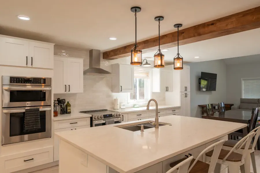 A kitchen with white cabinets , stainless steel appliances , and a large island.