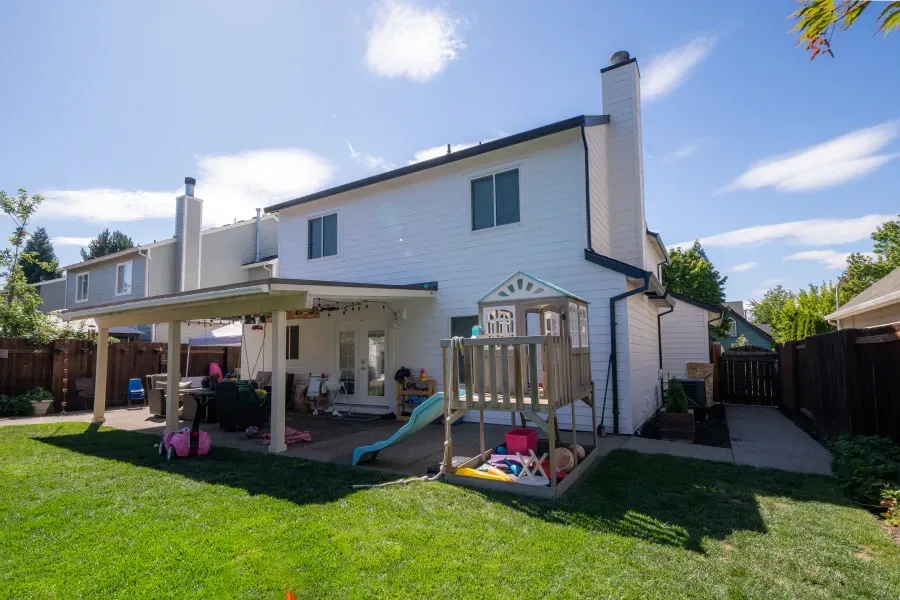The backyard of a house with a playground and a slide.