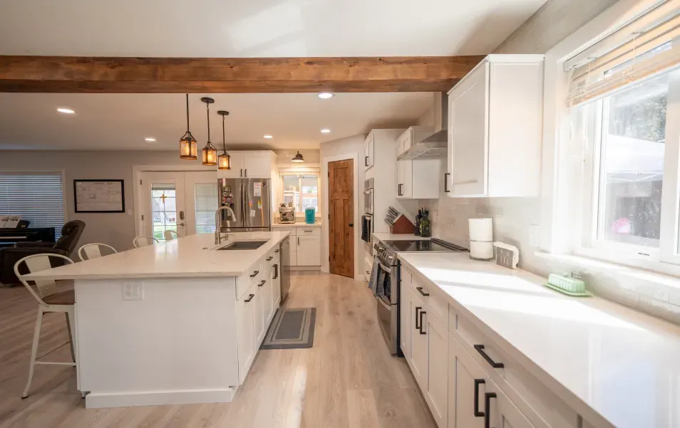 A kitchen with white cabinets , stainless steel appliances , and a large island.