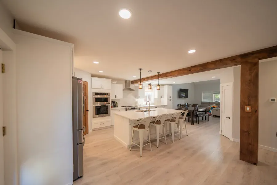 A kitchen with a large island and stools in a house.