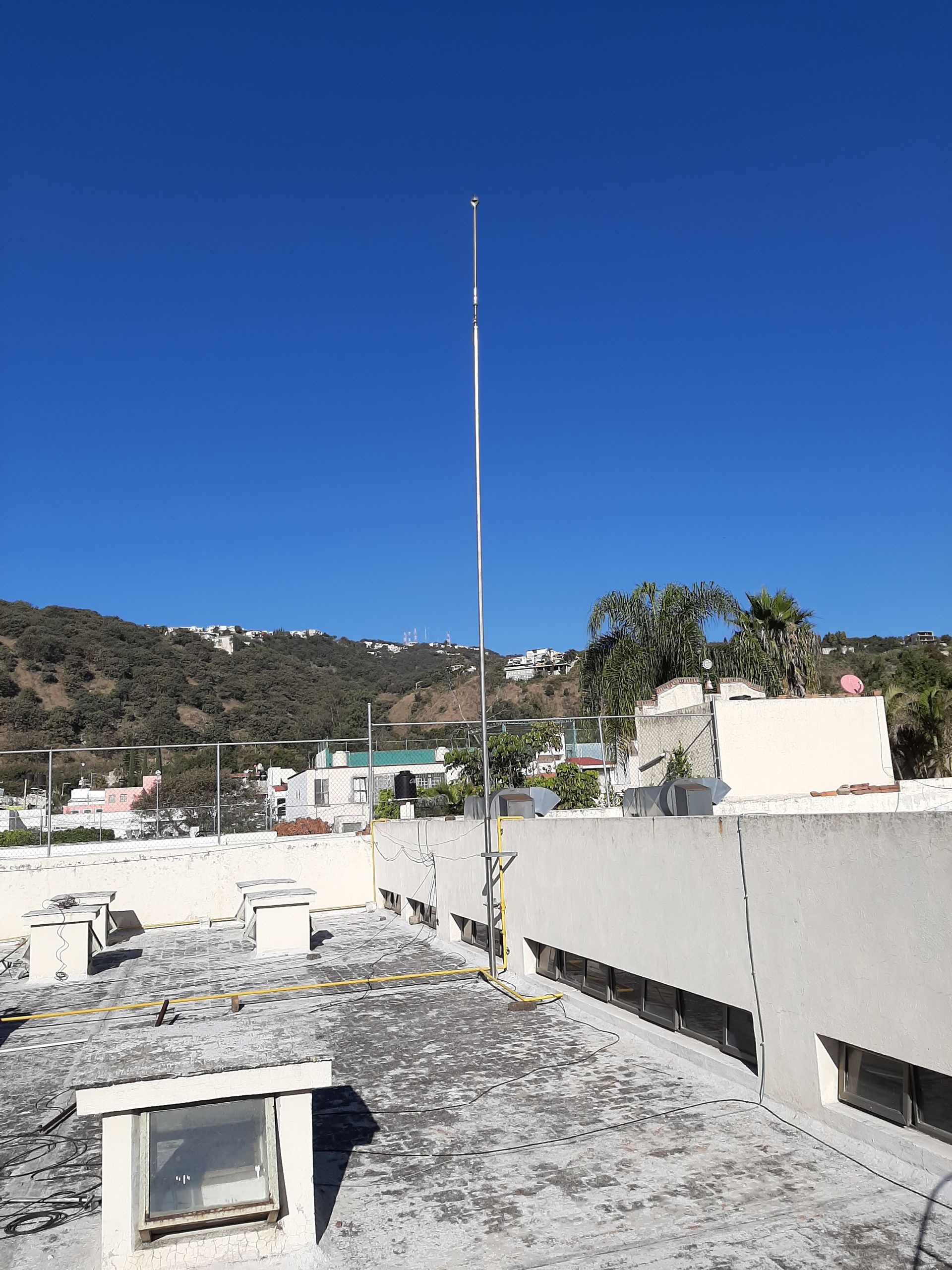 Un alto poste de metal está sentado en el techo de un edificio