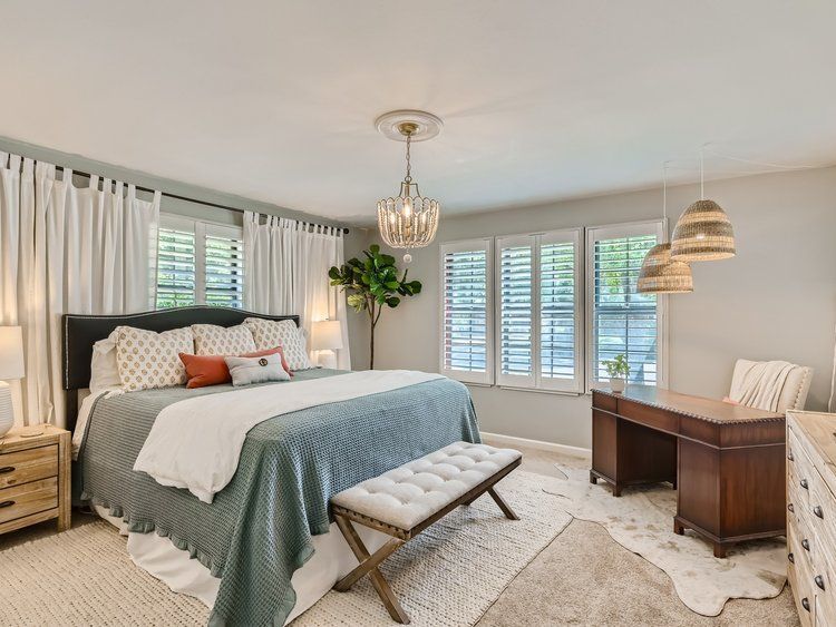 After interior design of Master Bedroom with beautiful plantation shutters, King bed, and antique desk.