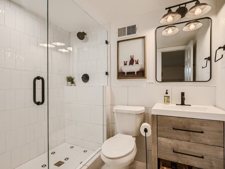 After Interior Design of Guest Bathroom in Basement. Extended shower size and relocated the door. Painted blue door paint. Penny tile black and white with flower design.