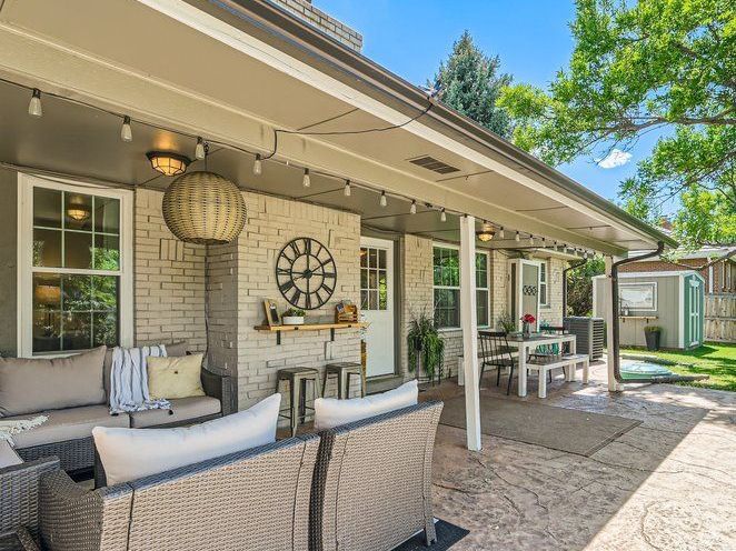 After Design of Backyard Patio. Updated exterior painted brick for modern look. Patio furniture for seating area and modern outdoor table for eating. Custom outdoor shelf or bar seating space. 