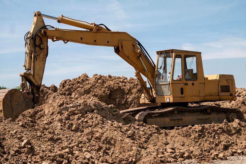 A yellow excavator is digging a pile of dirt on a construction site.