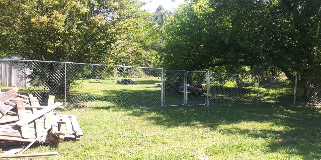 A backyard with a chain link fence and trees in the background.