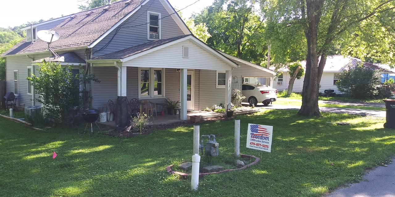 A small house with a porch and a sign in front of it.