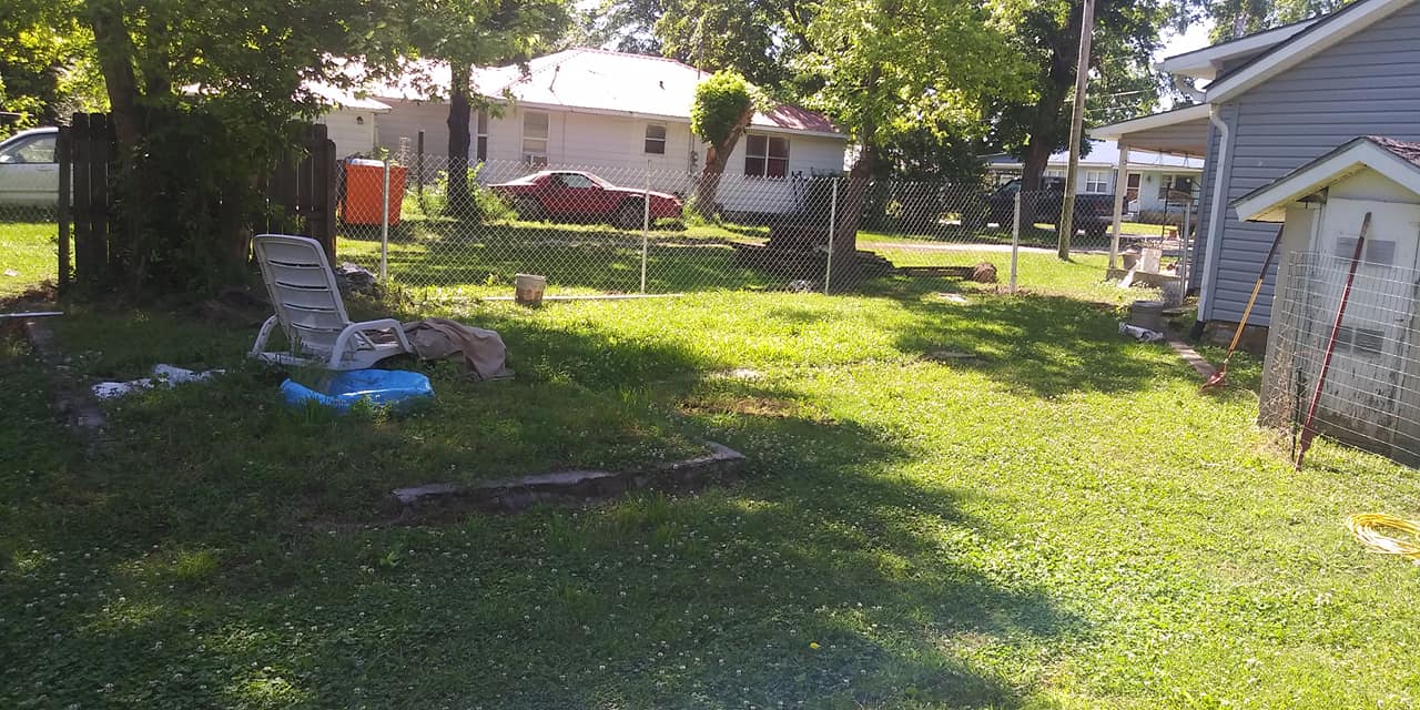 A backyard with a pool and a house in the background.