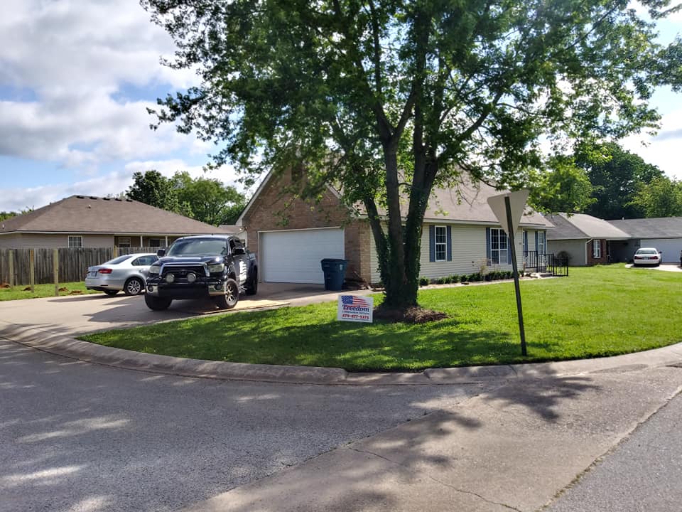 A truck is parked in front of a house with a sign that says i voted