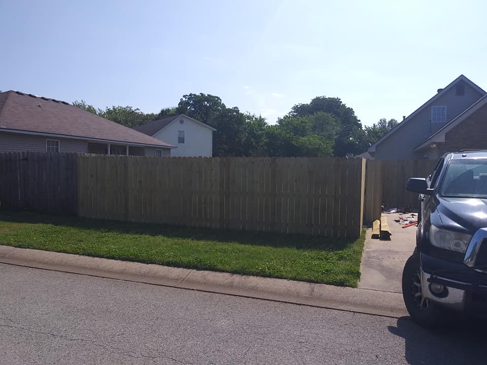 A black truck is parked in front of a wooden fence