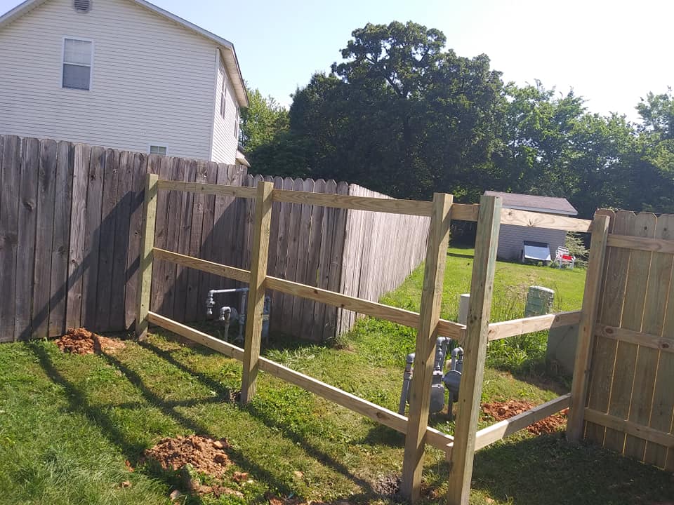 A wooden fence is being built in the backyard of a house.