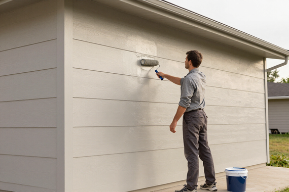 Professional painter applying clean coat to exterior home facade