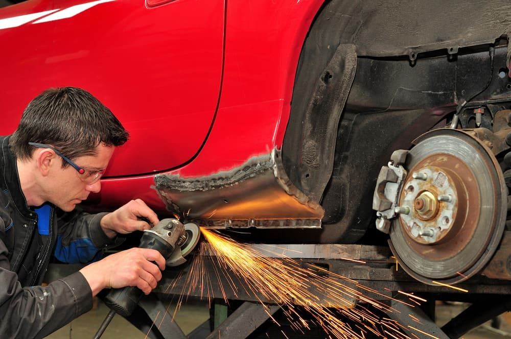 A Man Is Grinding The Side Of A Red Car — Banora Automotive In Tweed Heads South, NSW