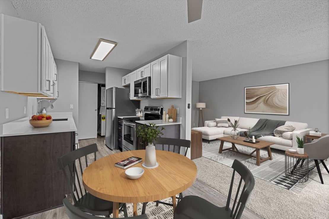 A living room with a dining table and chairs and a kitchen.