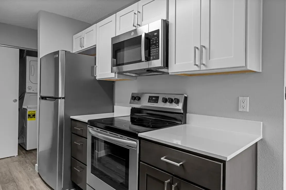 A kitchen with stainless steel appliances and white cabinets.