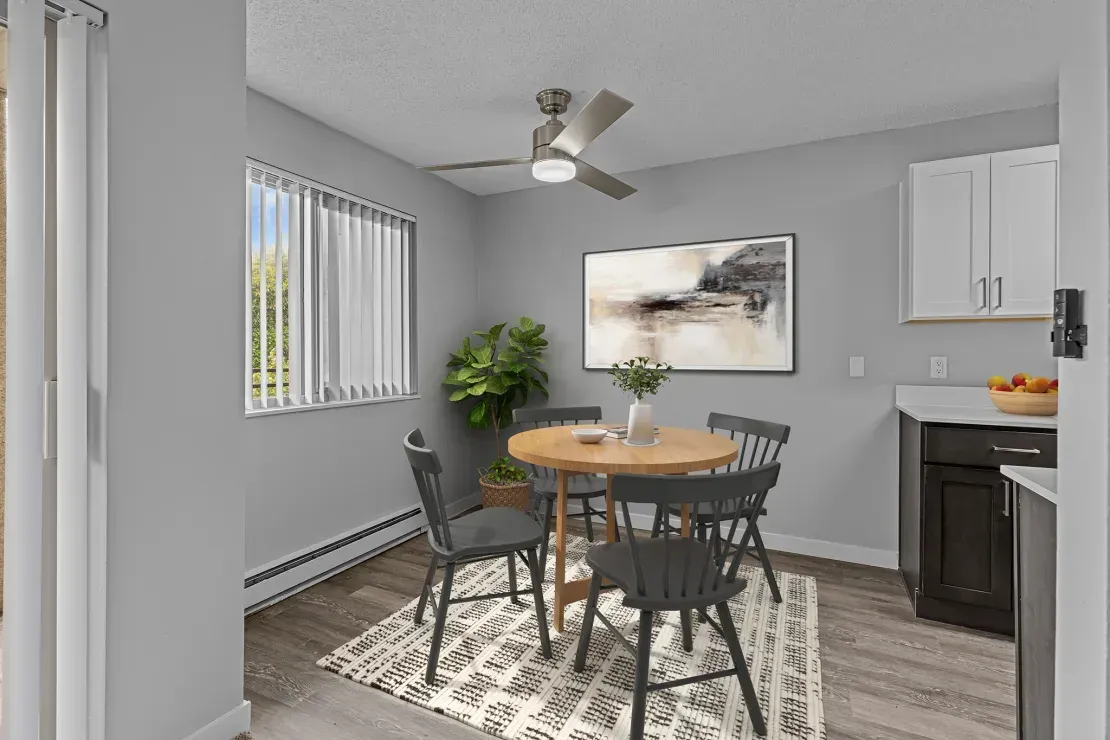 A dining room with a table and chairs and a ceiling fan.