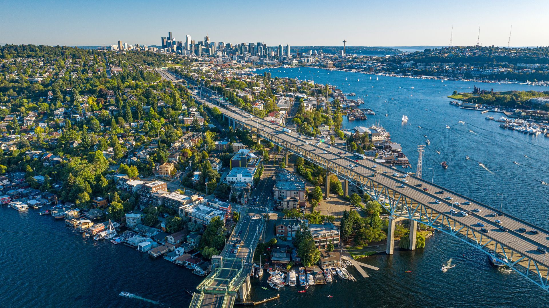 An aerial view of a bridge over a body of water with a city in the background.