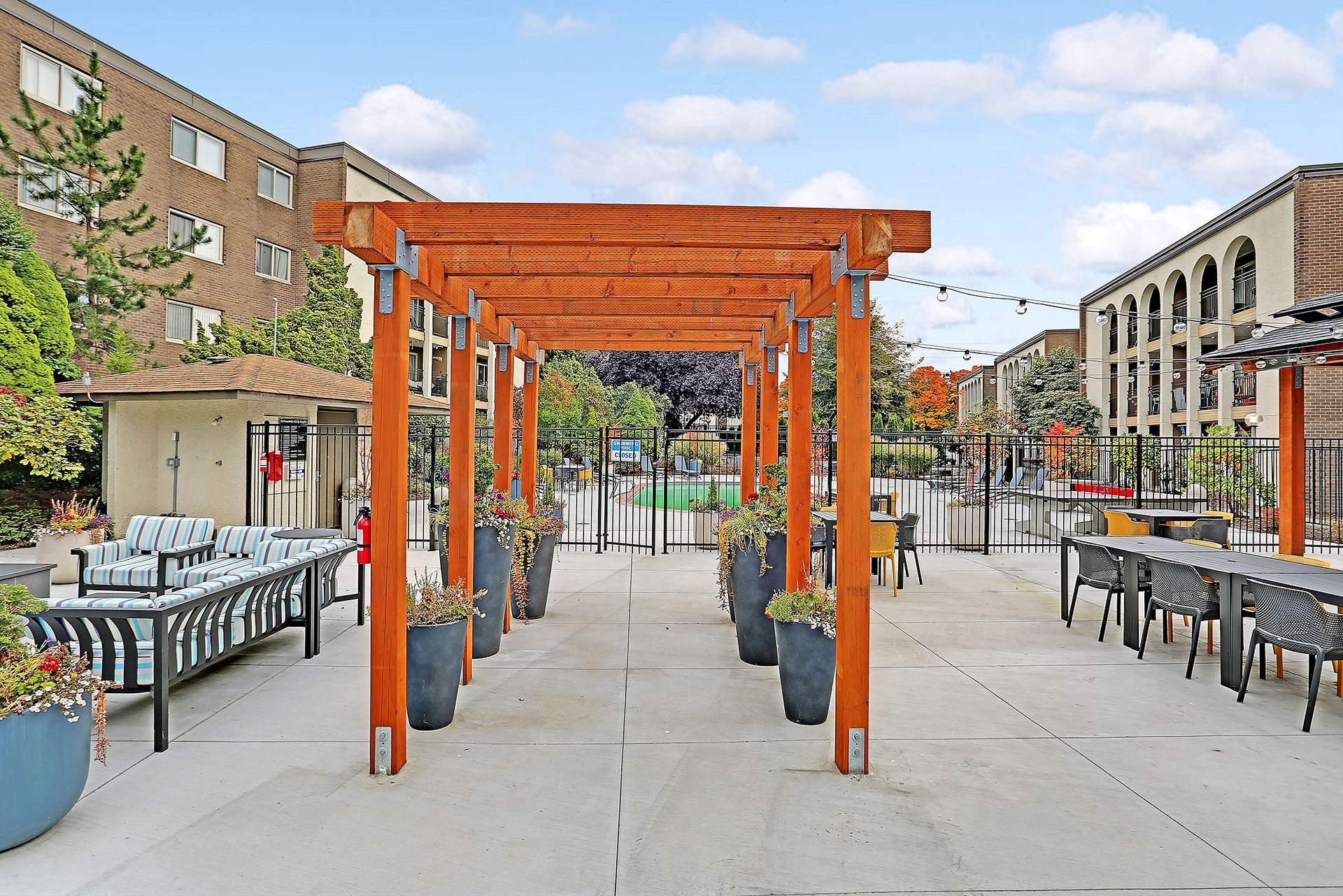 There is a wooden pergola in the middle of a courtyard.